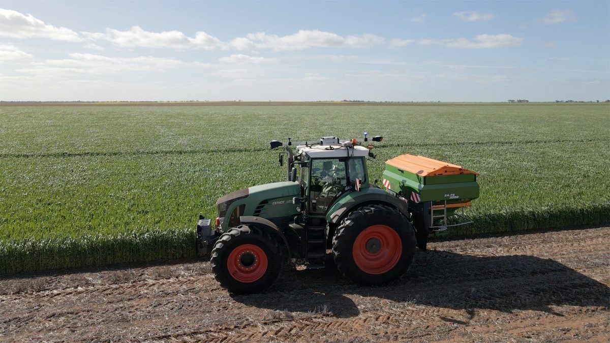 Fendt tractor fitted with an Ornata kit, with a spreader beside a green crop